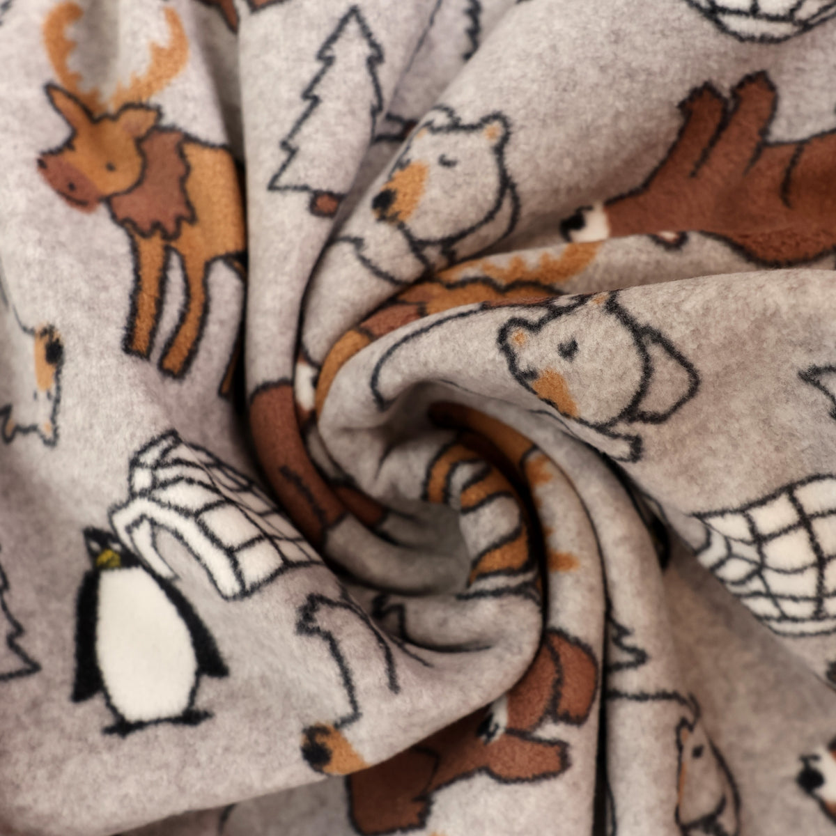 A close-up of a soft fleece blanket with a woodland animal print, featuring polar bears, a penguin, a moose, and a bear on a light gray background.