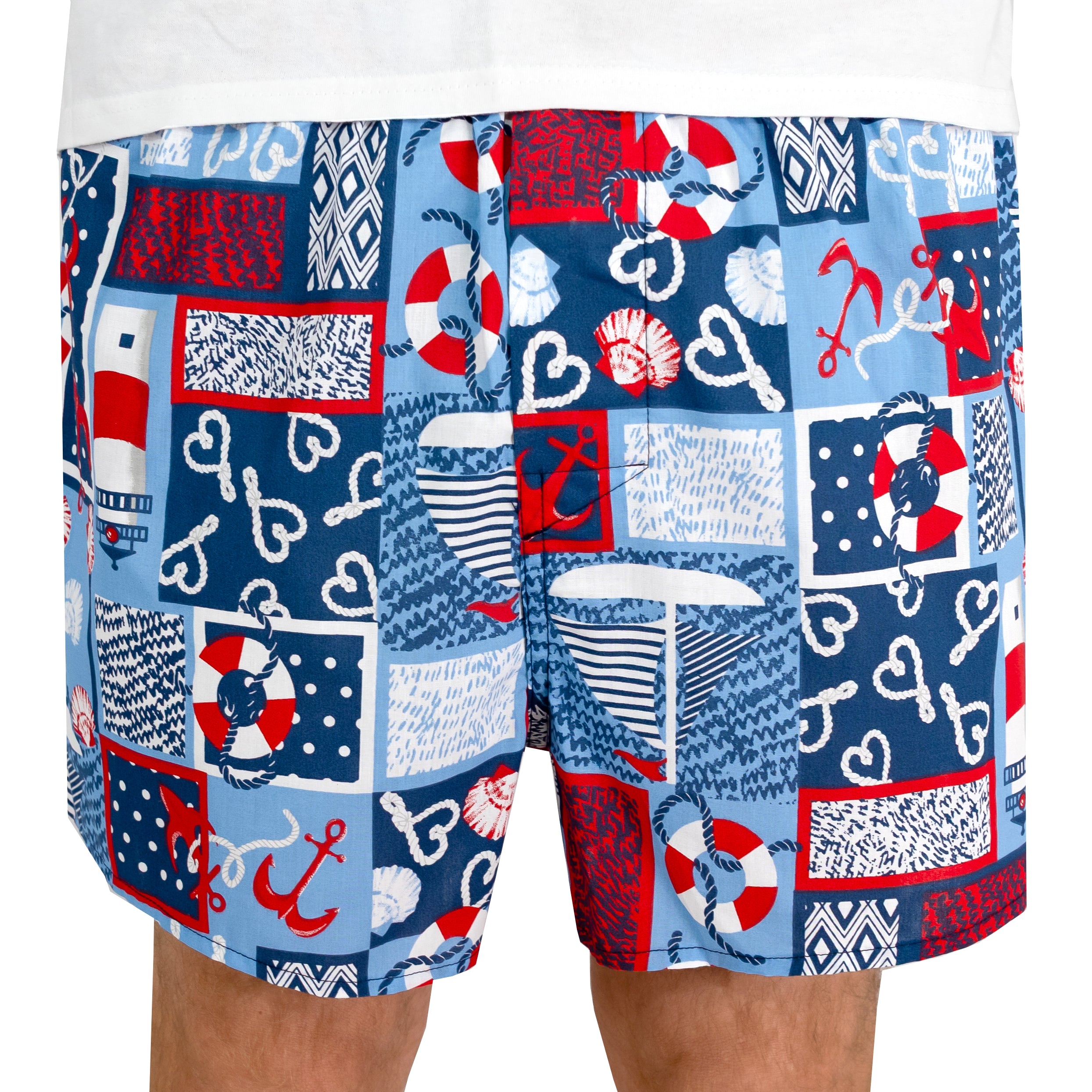 Men's nautical-themed patchwork print boxer shorts featuring red, white, and blue patterns of anchors, life buoys, hearts, and stripes, worn by a model.